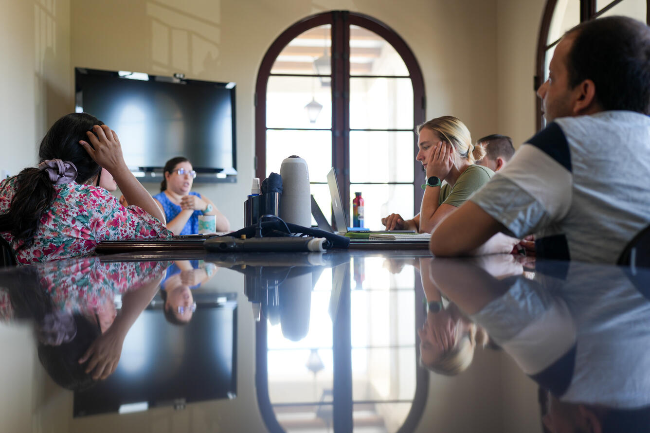 Five people are talking around a long conference table.