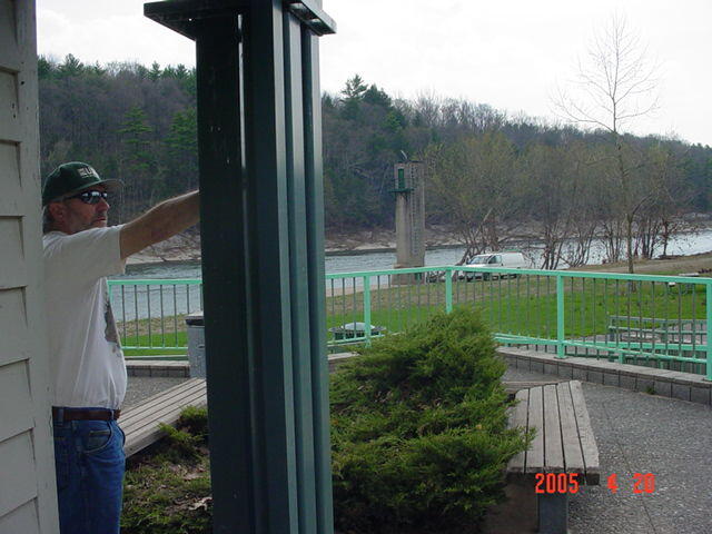 A man pointing out how high the river got on the Beach Office and showing the gage house in the background