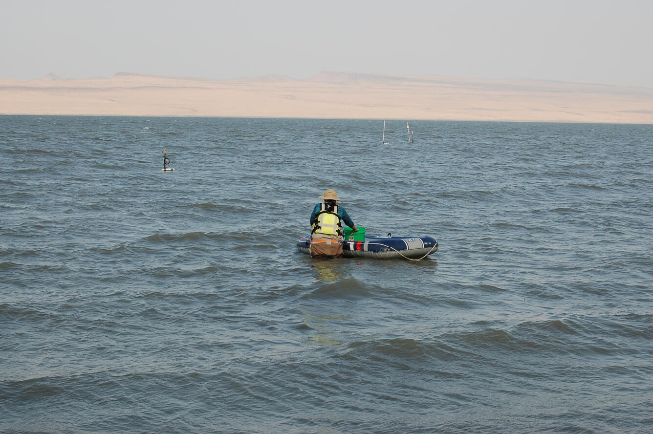 Person pushes a raft with equipment out to equipment in thigh deep choppy water