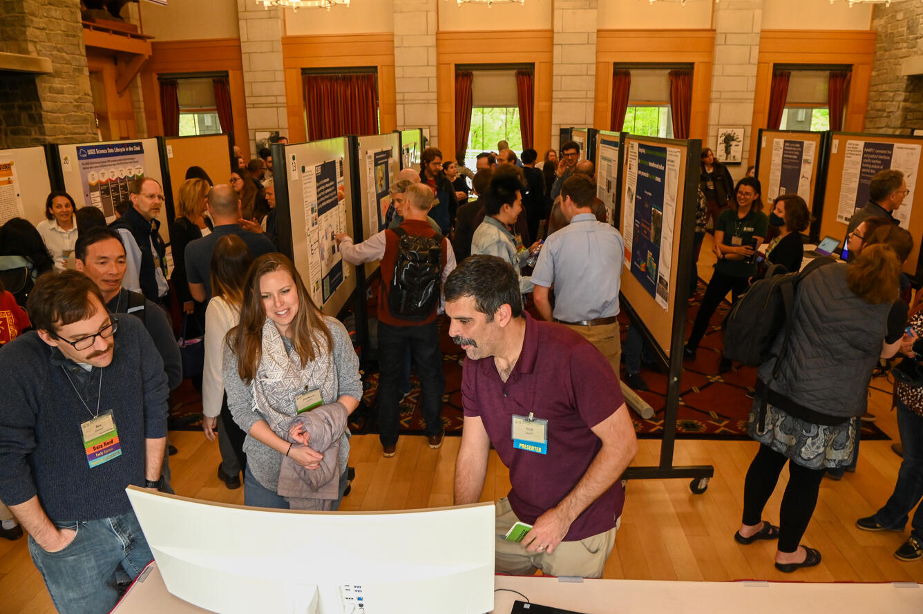 Photo of a poster session at the 2023 CDI Workshop with participants milling around posters in a large room.