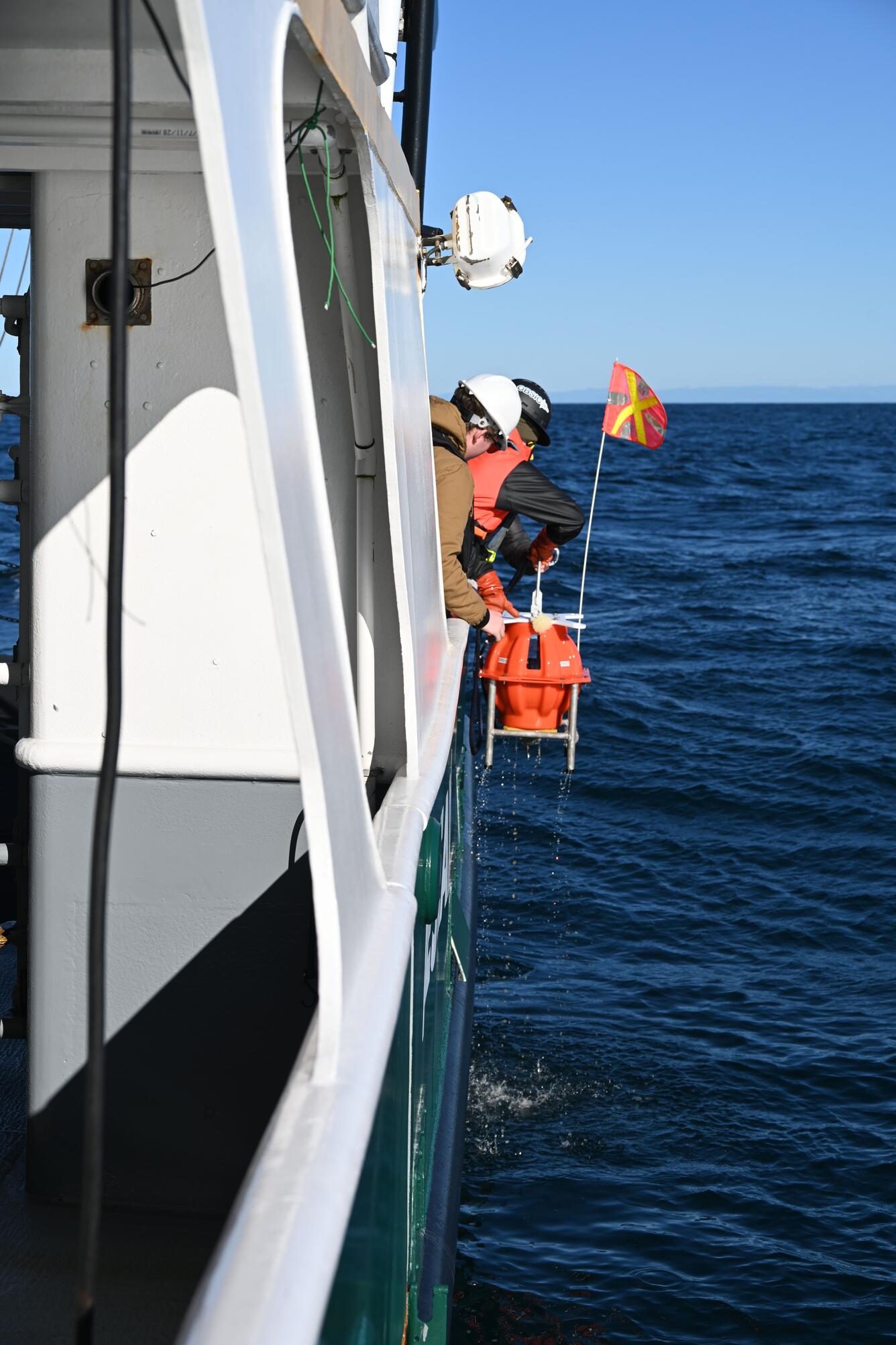 people retrieving small piece of equipment from the ocean