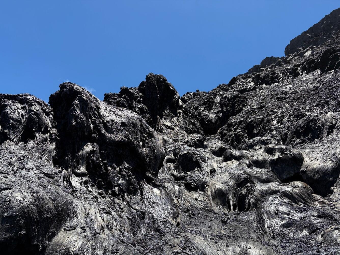 Color photograph of black cooling lava from the August 6th eruption. 