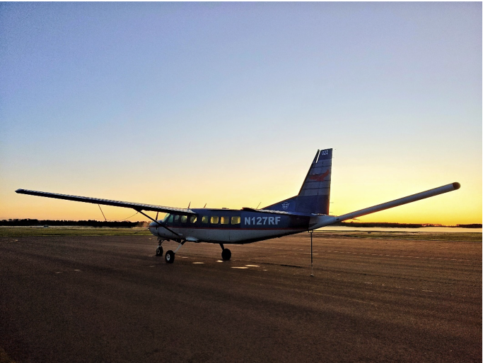 Airplane parked on the ground at daybreak (or sunset).
