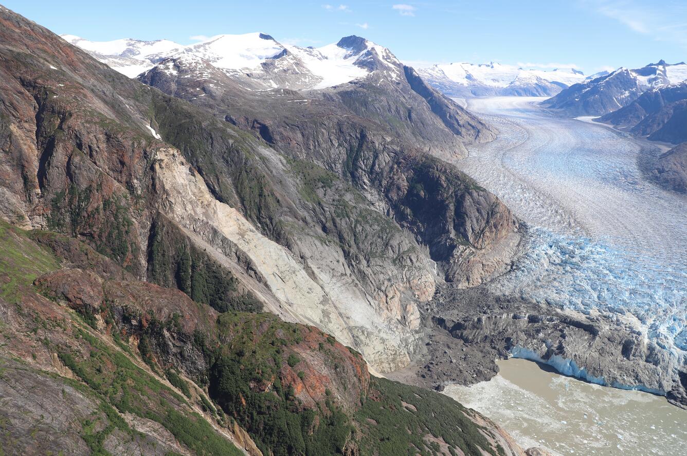Photo of mountainside with landslide in the center and glacier to the right