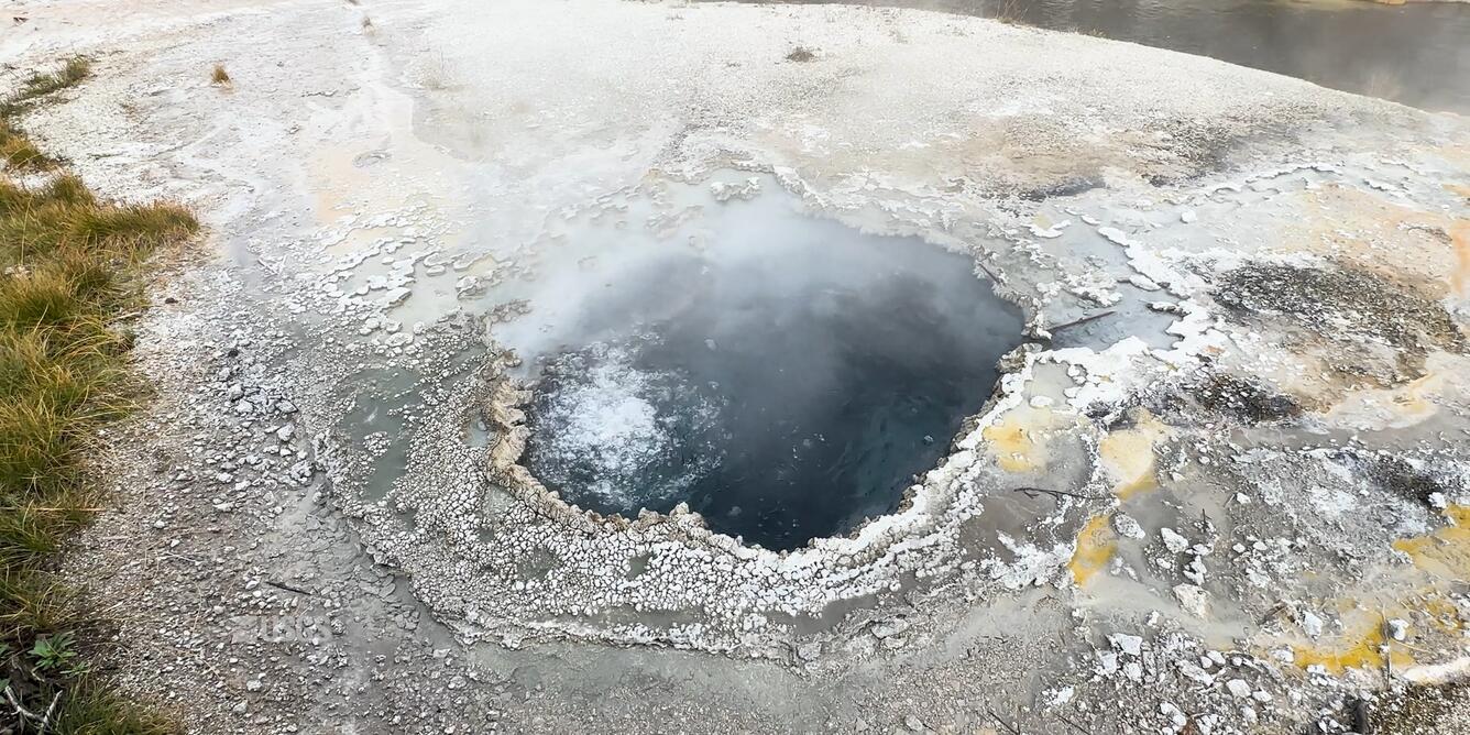 A blue water-filled hold with bubbling water surrounded by small, bumpy surface area.