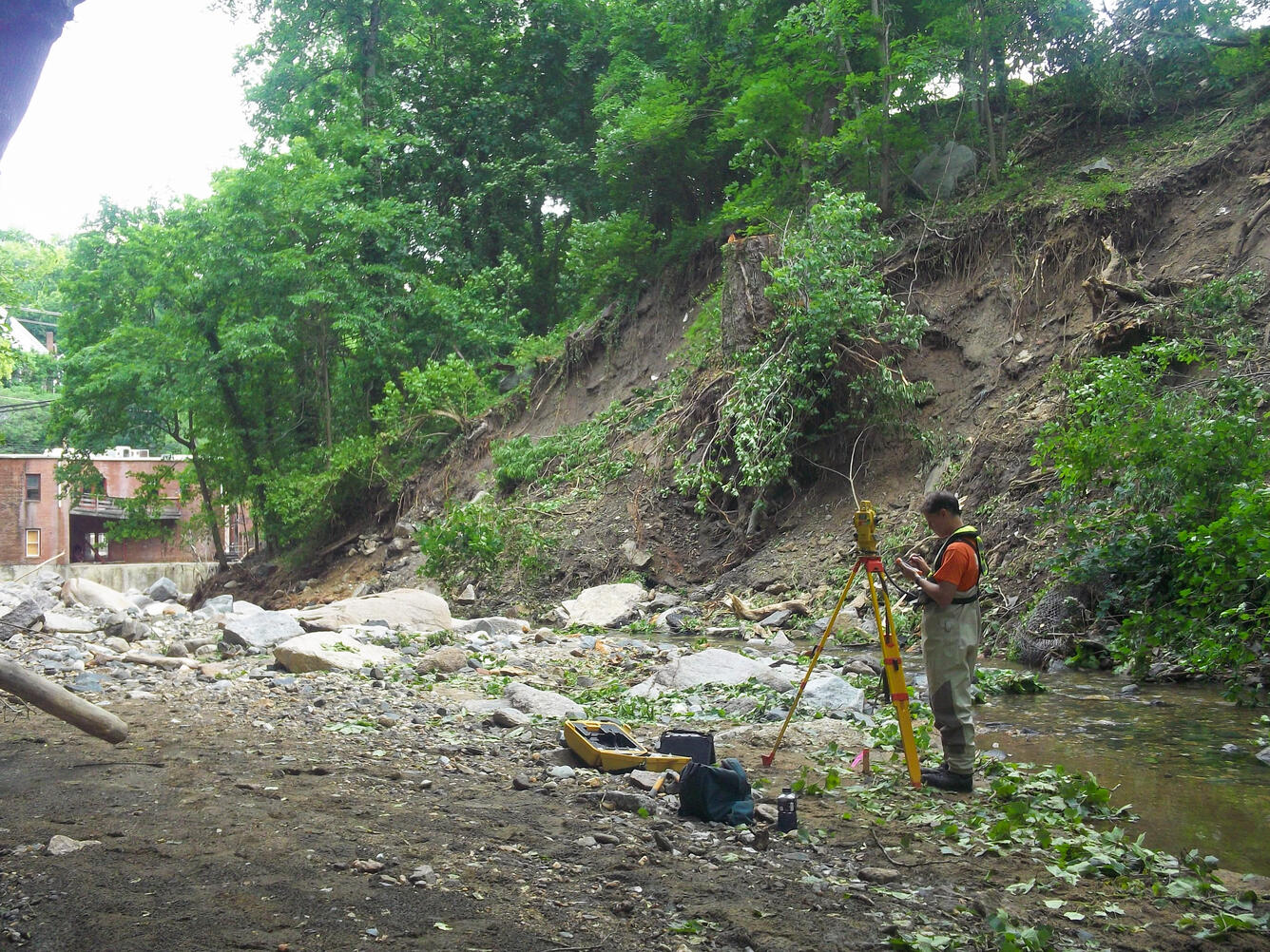 A USGS hydrologic technician sets up survey equipment in a stream channel.