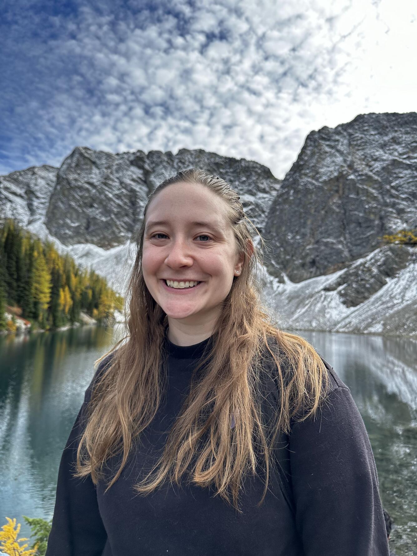 smiling girl with long hair with background of lake and mountains