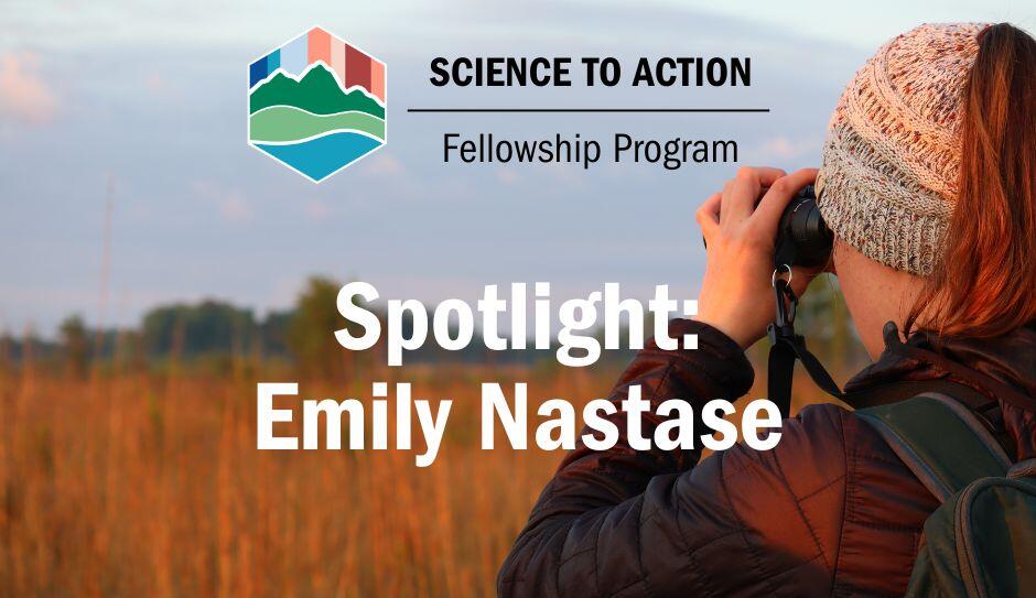 Emily Nastase, a woman with brown hair under a knit hat, looks through a pair of binoculars.