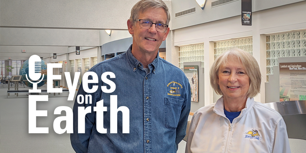 Logo with man and woman standing in bright atrium at EROS
