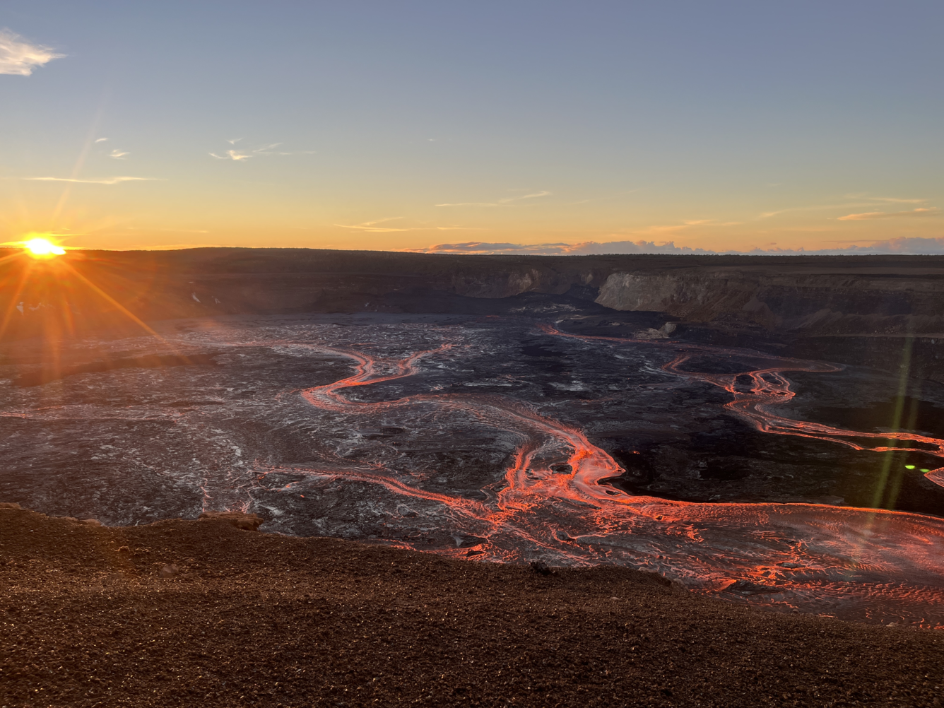 Color photograph of lava flowing in volcanic crater at sunrise