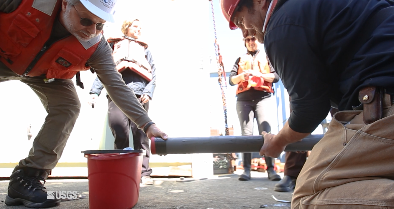 Two workers guide a pipe