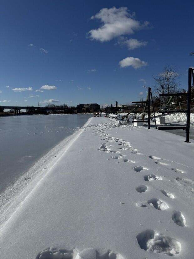 Footprints in snow next to a frozen river.