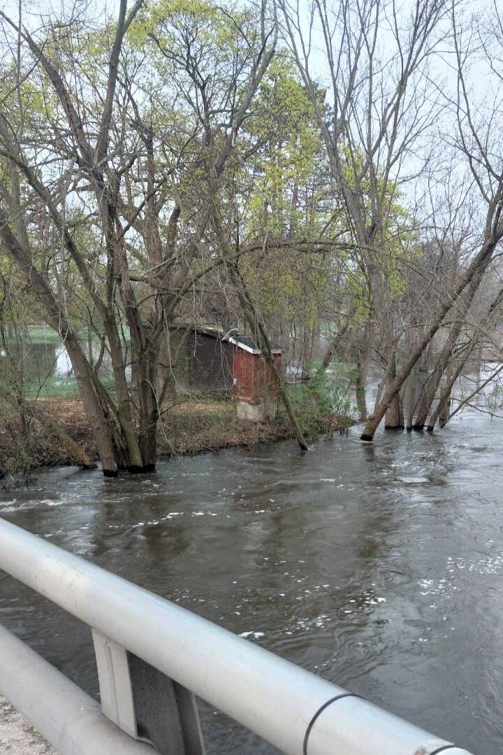 Red streamgage housing on banks of a flooded river