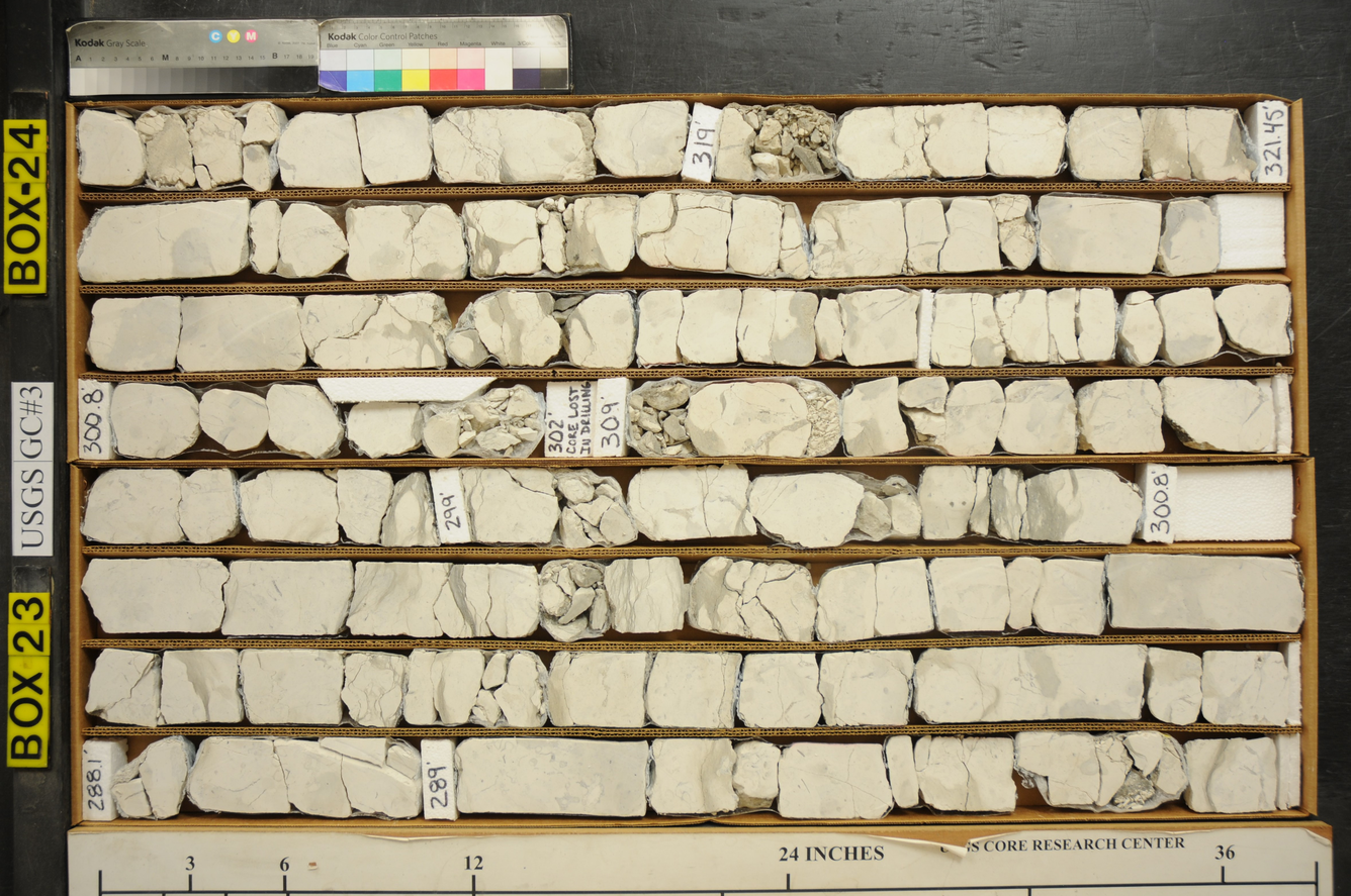 Box with irregular, rectangular sections of white rock. The rock is drill core - samples of rock drilled at different depths