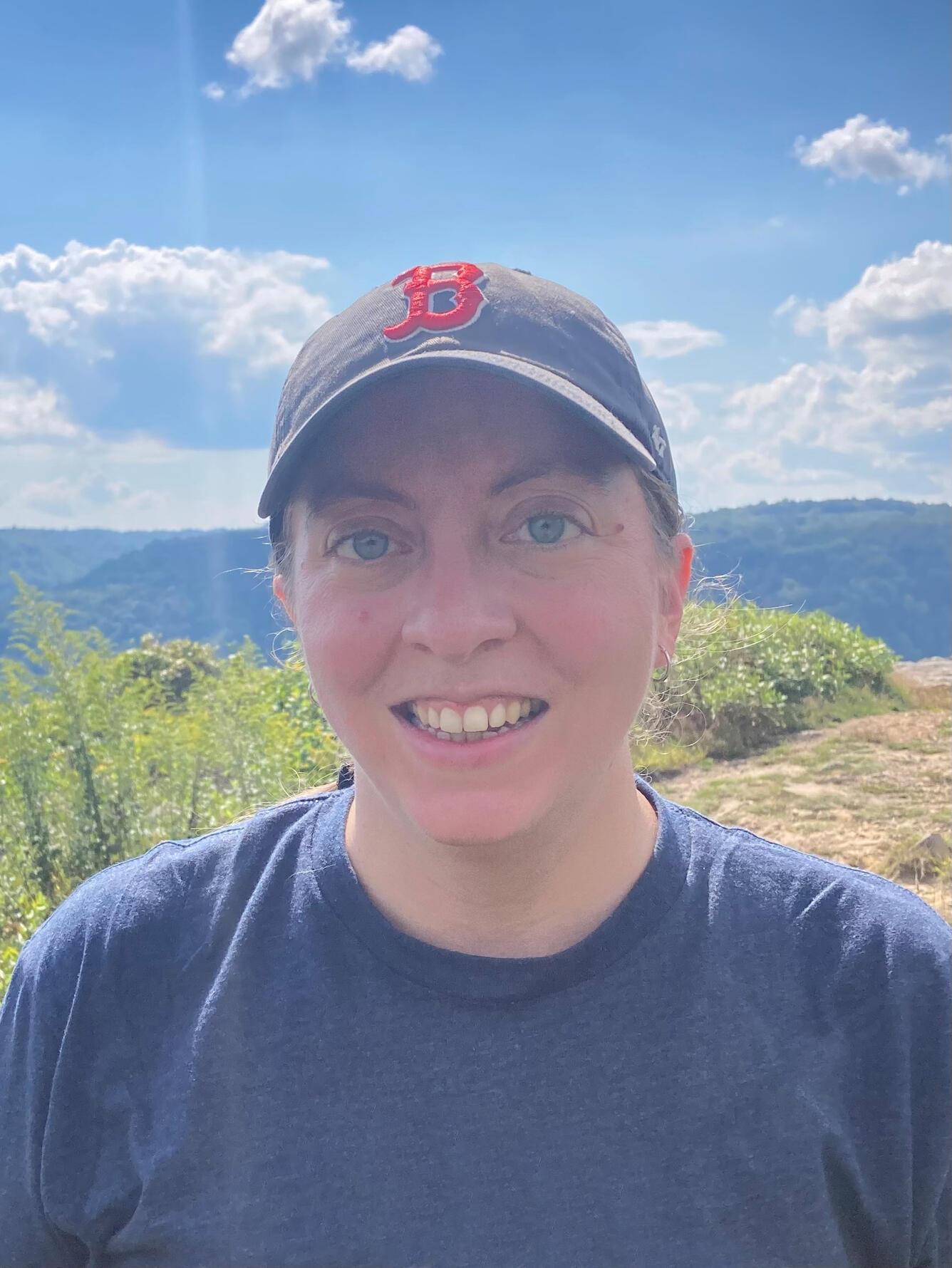 woman wearing a blue hat standing near the mountains