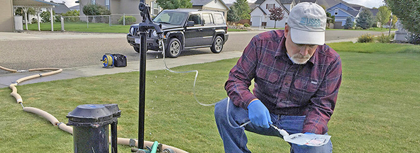 A U.S. Geological Survey hydrologist collects a water sample