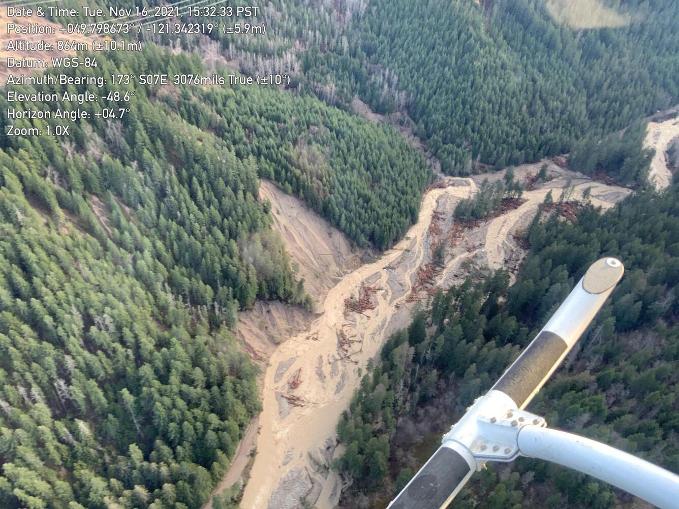 aerial view of muddy braided river surrounded by tree-covered hillslopes