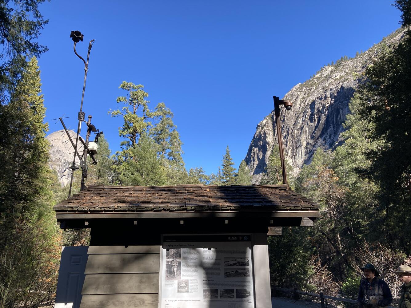 Wooden hut structure with cameras on top of it in front of a rocky mountain