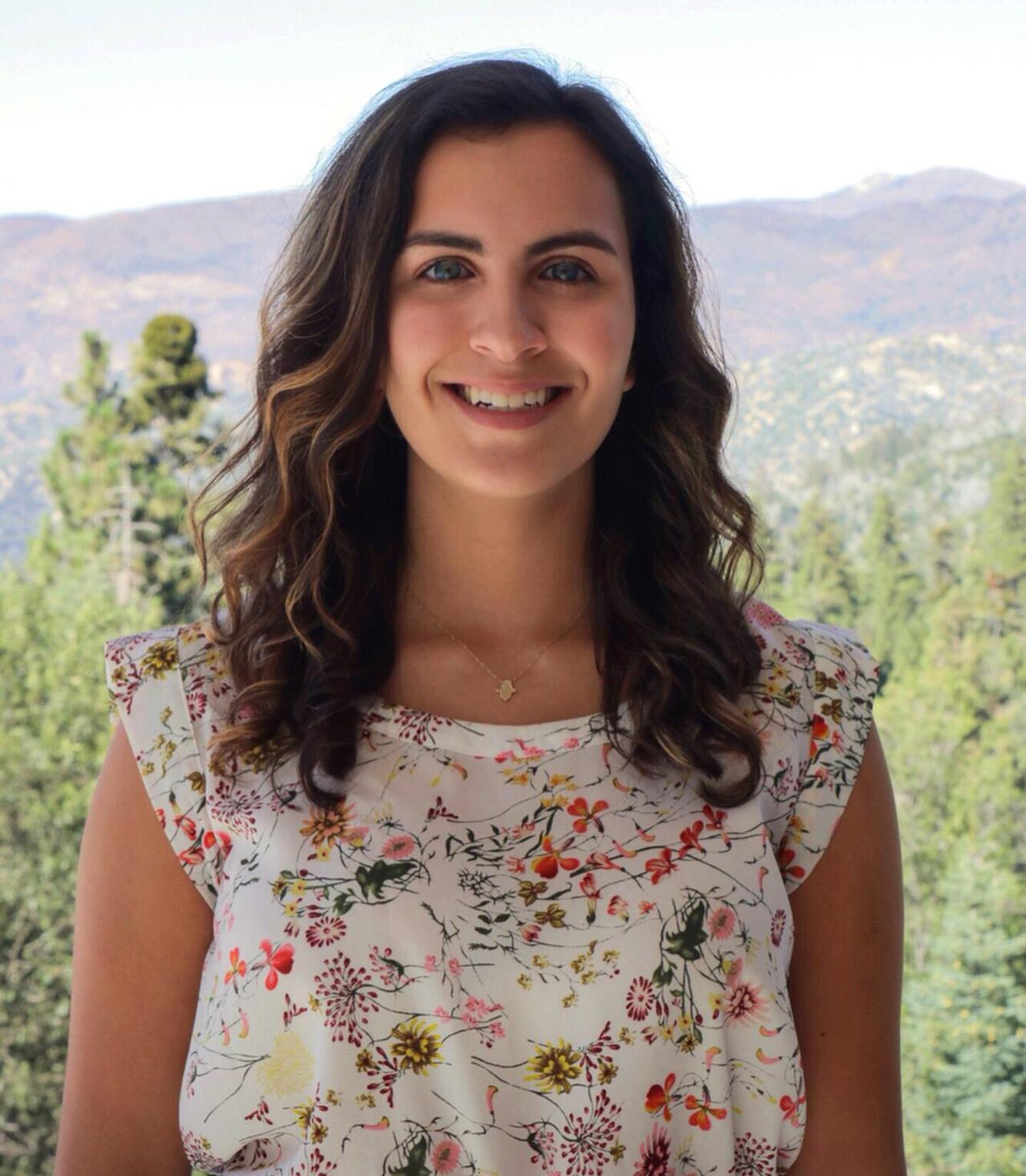 A headshot of Isabella Caltabiano in a floral dress.