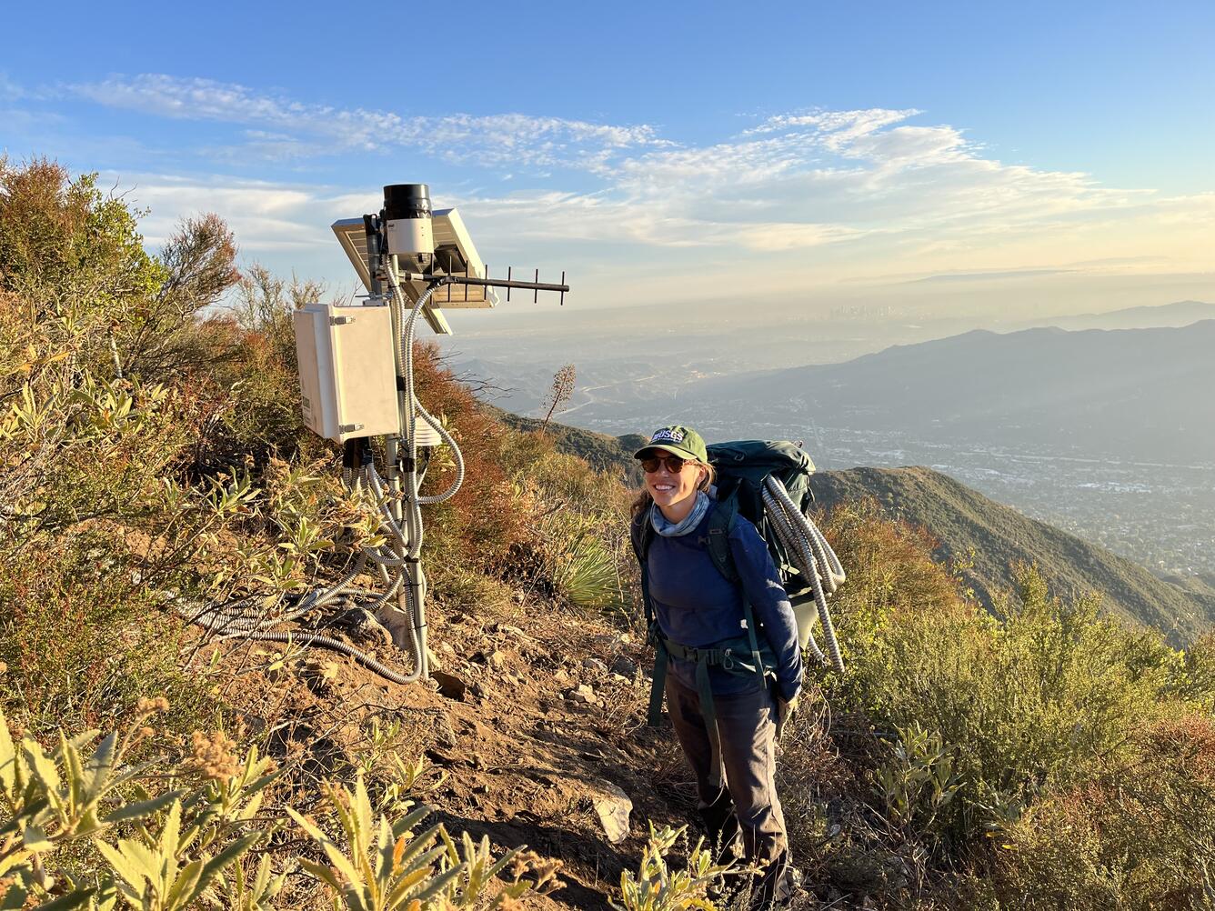 person standing on hillside next to monitoring equipment