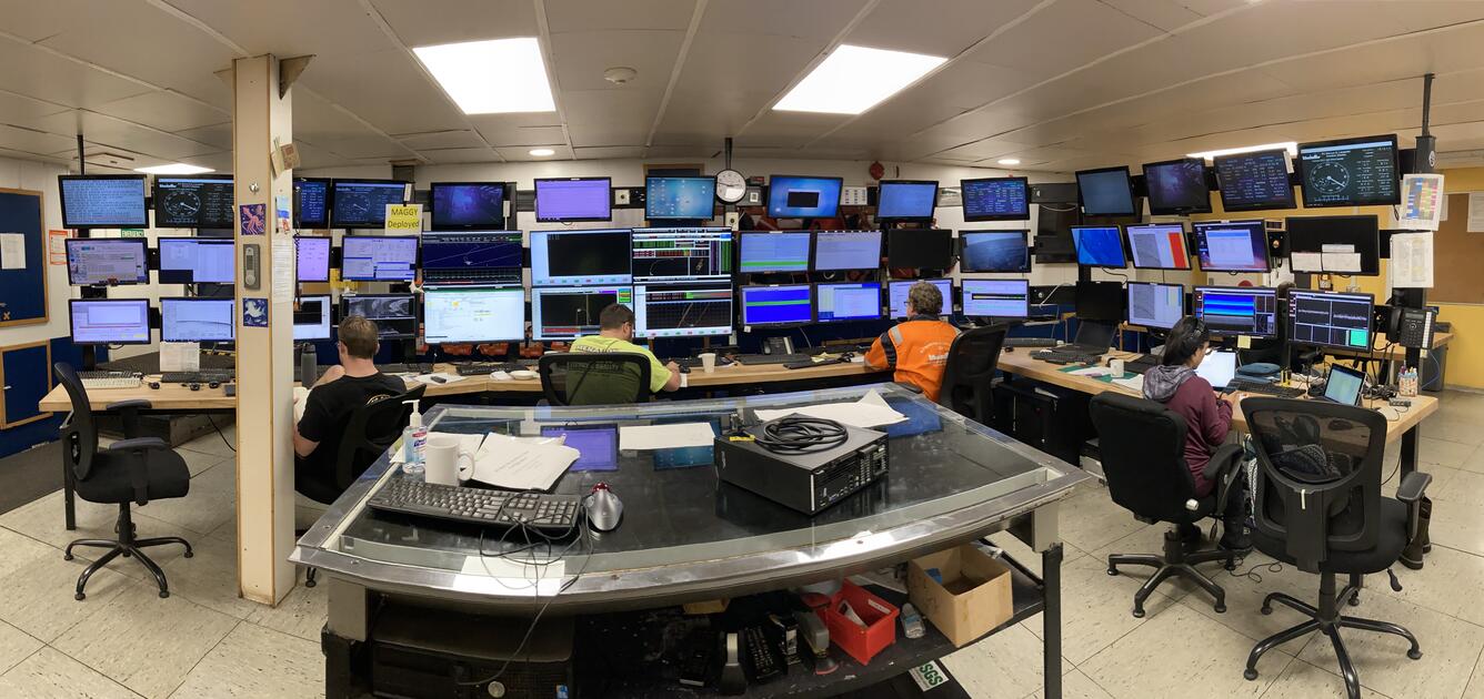 Four scientists sit in front of 44 computer screens to monitor seismic operations