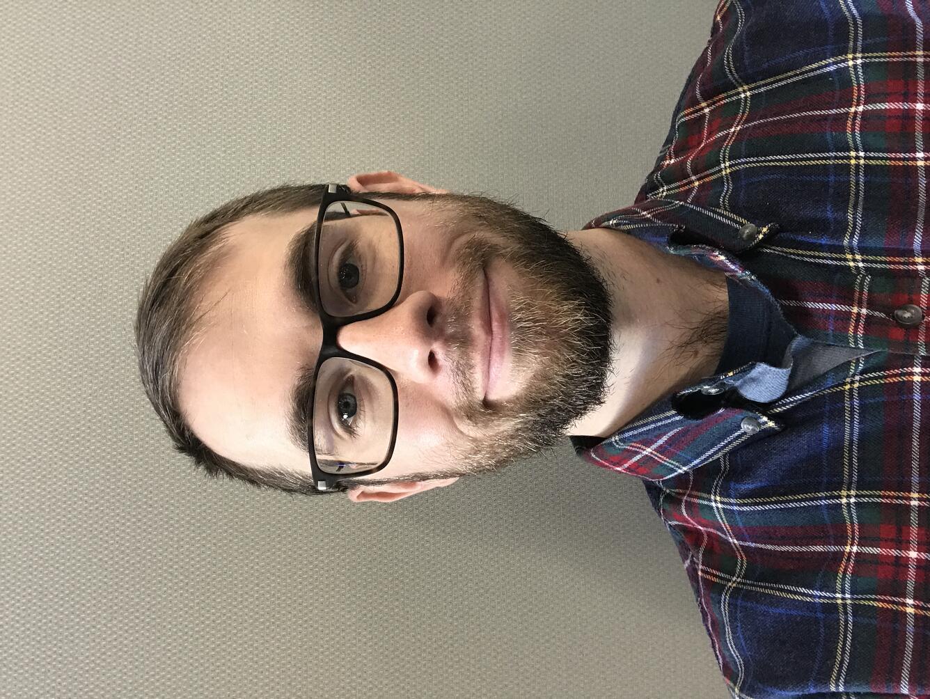 Young man with beard wearing glasses and plaid shirt