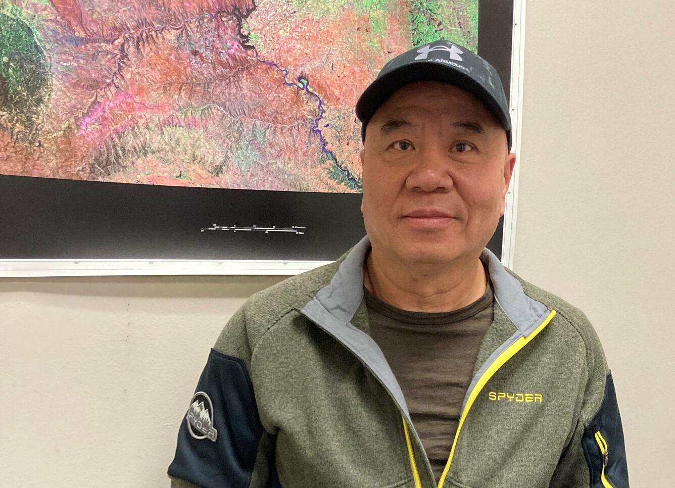 Man wearing a hat standing in front of a colorful map that's framed