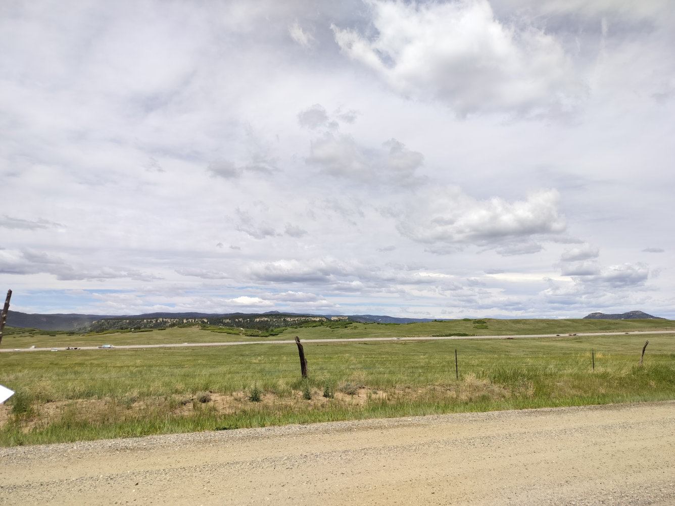 Grassy landscape with a road in the distance and cloudy skies