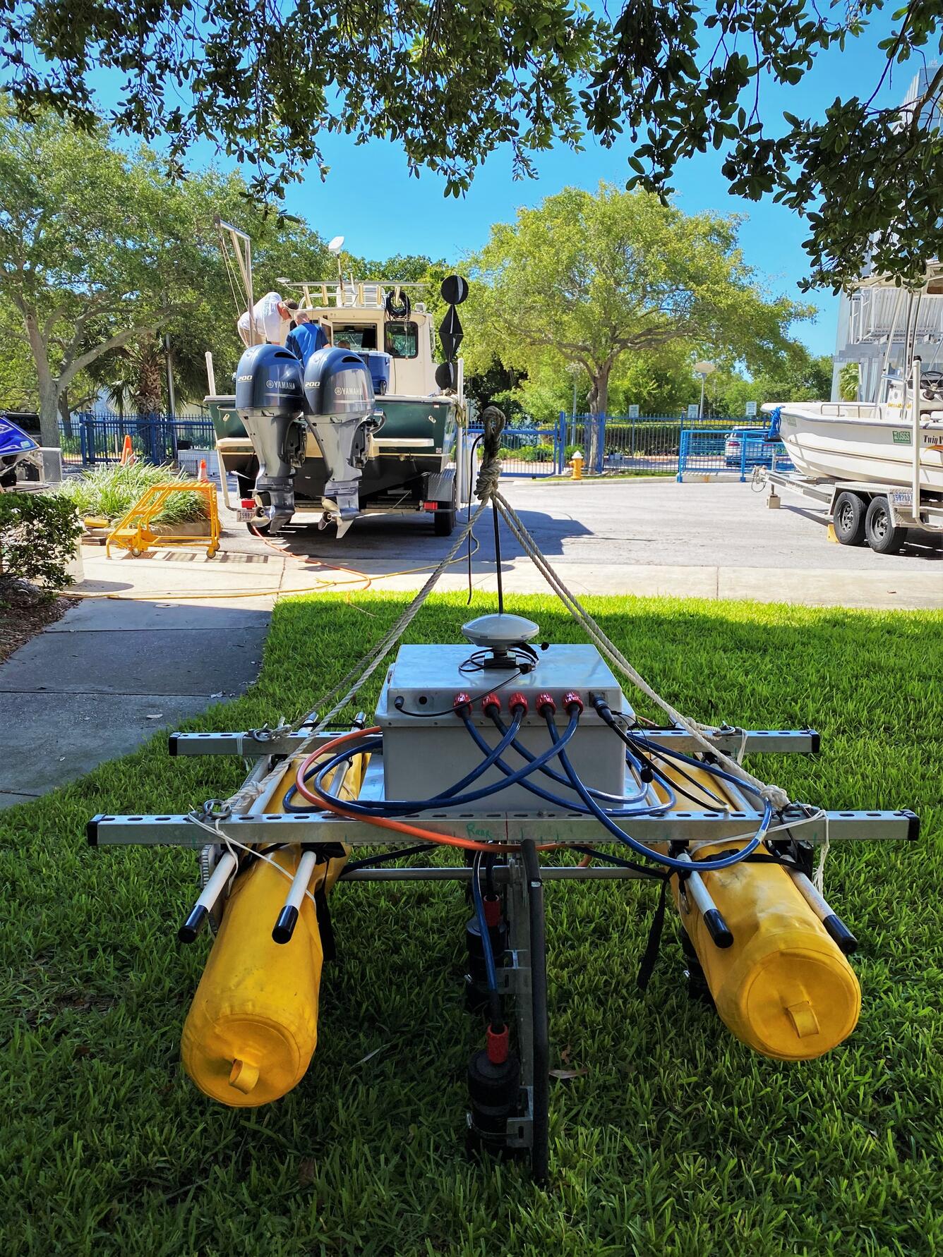 Scientific equipment mounted on two yellow tanks is sitting on a grassy lawn waiting for deployment in the bay