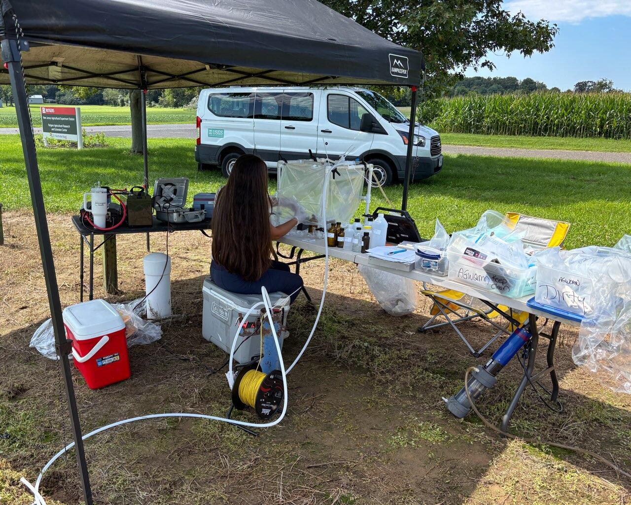 USGS Scientist collecting groundwater samples within a protective housing in the field