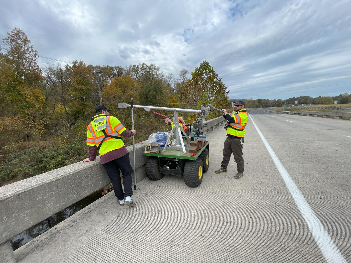 USGS scientists using a vehicle-mounted reel to retrieve a bedload sampler which has been deployed in a river.