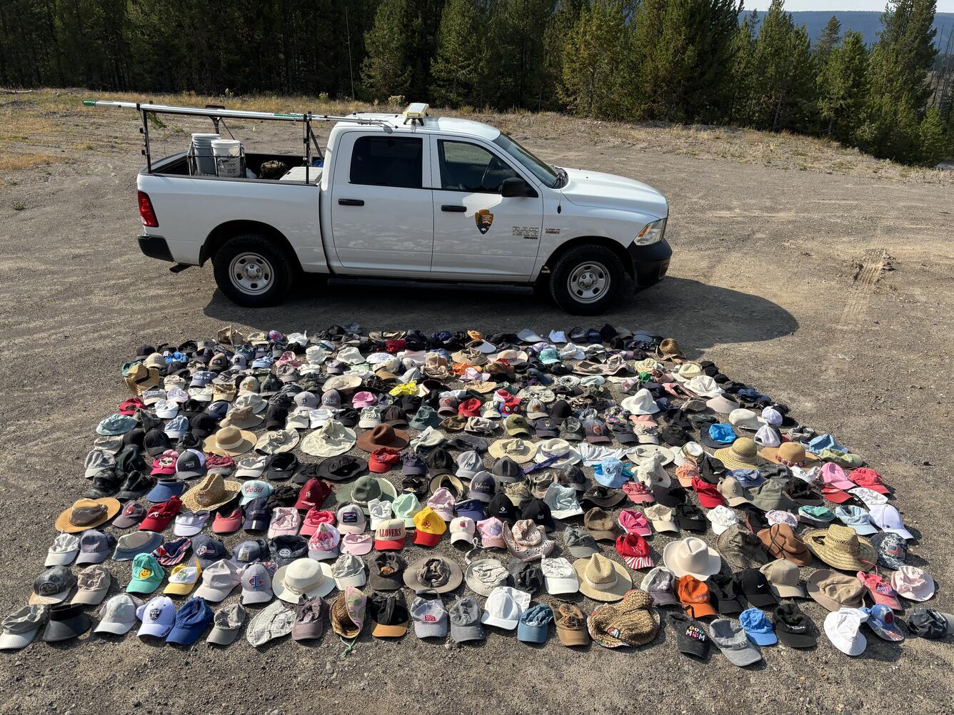 Hundreds of hats laid out for display with a truck in the background providing a sense of scale