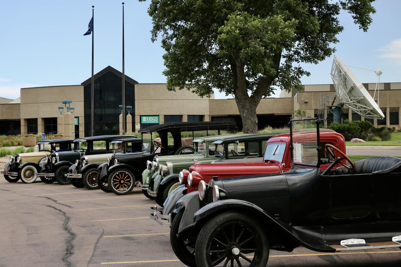 A lineup of classic cars in front of a building