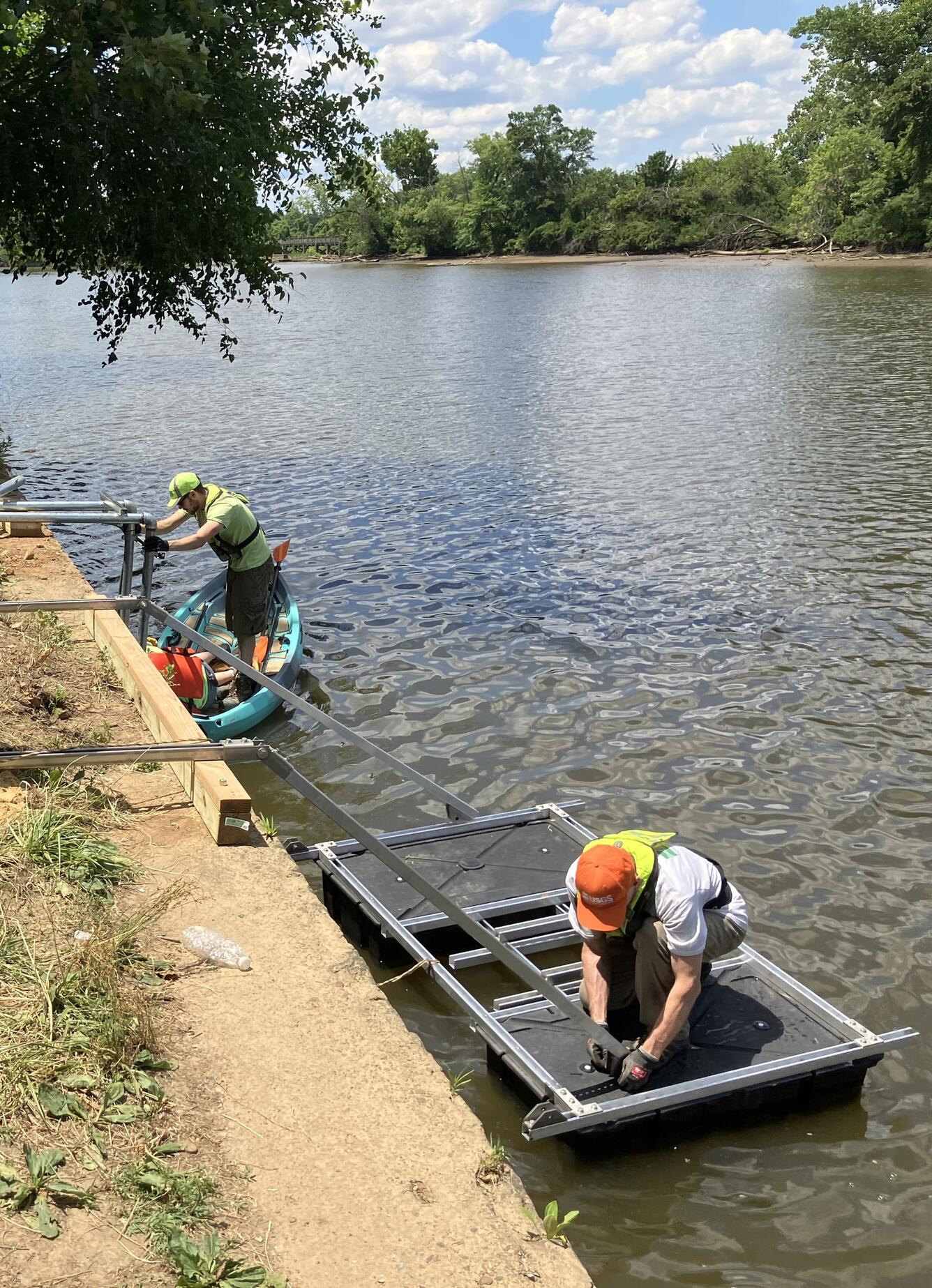 Workers building a gage on the water.