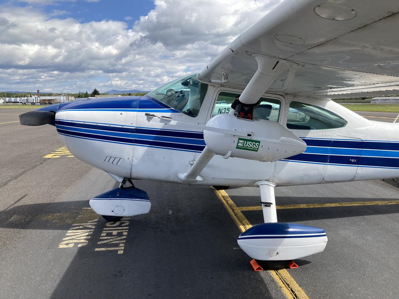 a small white aircraft with a blue, white, and black stripes running down the middle and plane nose.