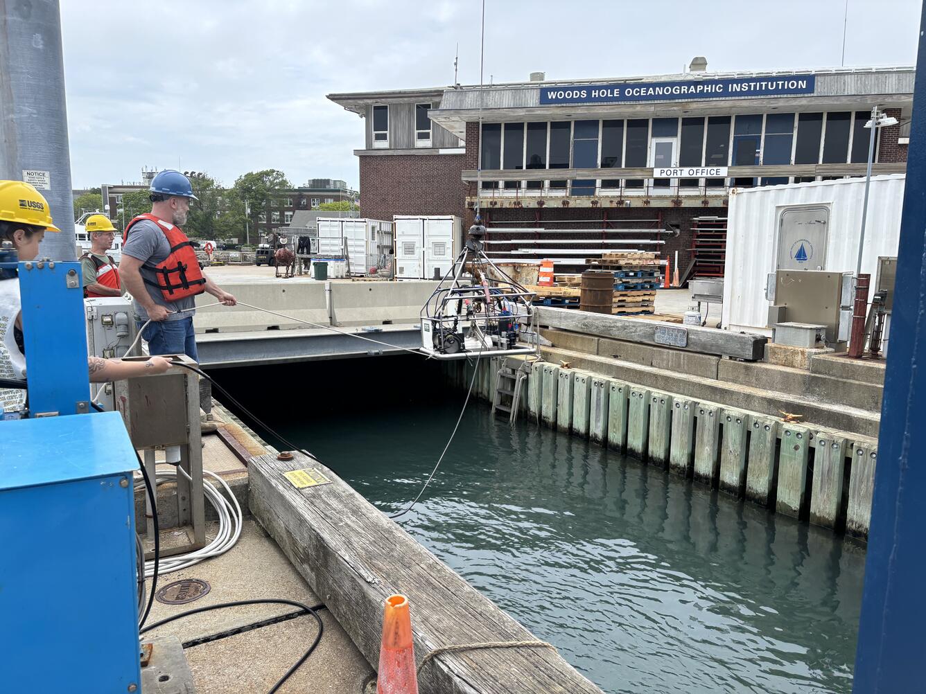 Equipment being lowered into the water by people on a dock