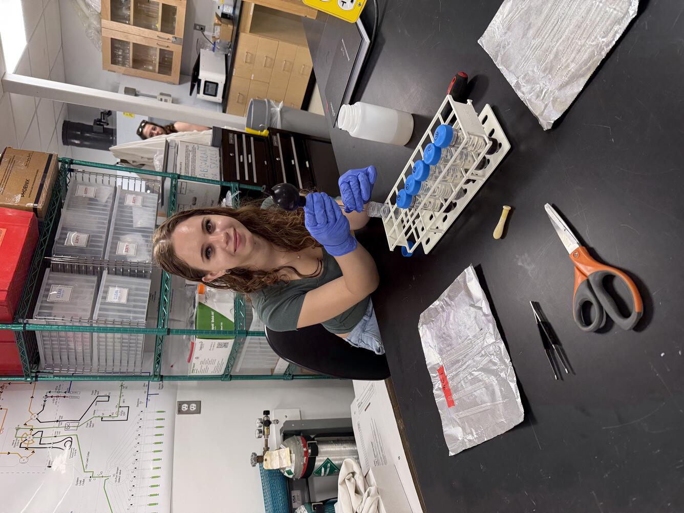 Intern working in a lab smiling to have her picture taken