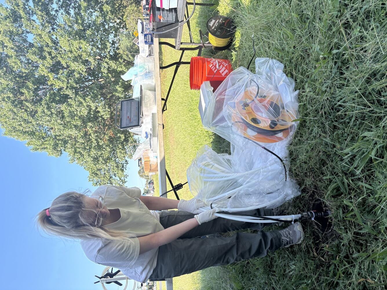 USGS scientist lowers hoses from a pump wrapped in protective plastic down into a well
