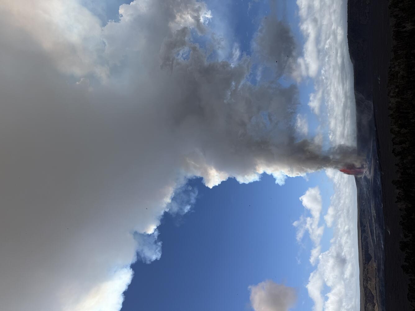 Large white plume of volcanic gas and steam rising from lava fountains in a crater