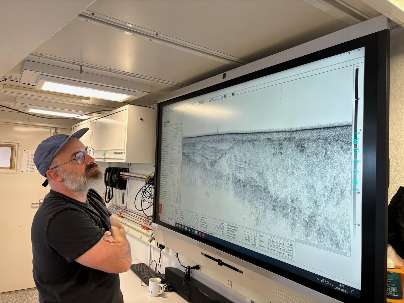 Man looking at a subbottom profile data on a large screen