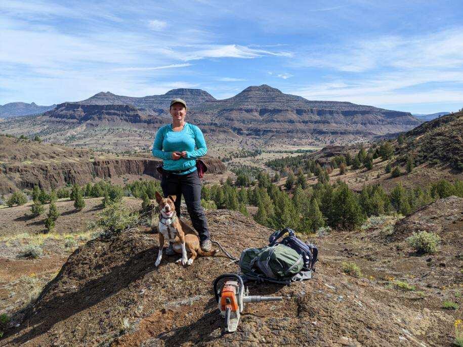 Geophysicist doing fieldwork in the Columbia River Basalt, standing on ridge with field equipment and landscape.