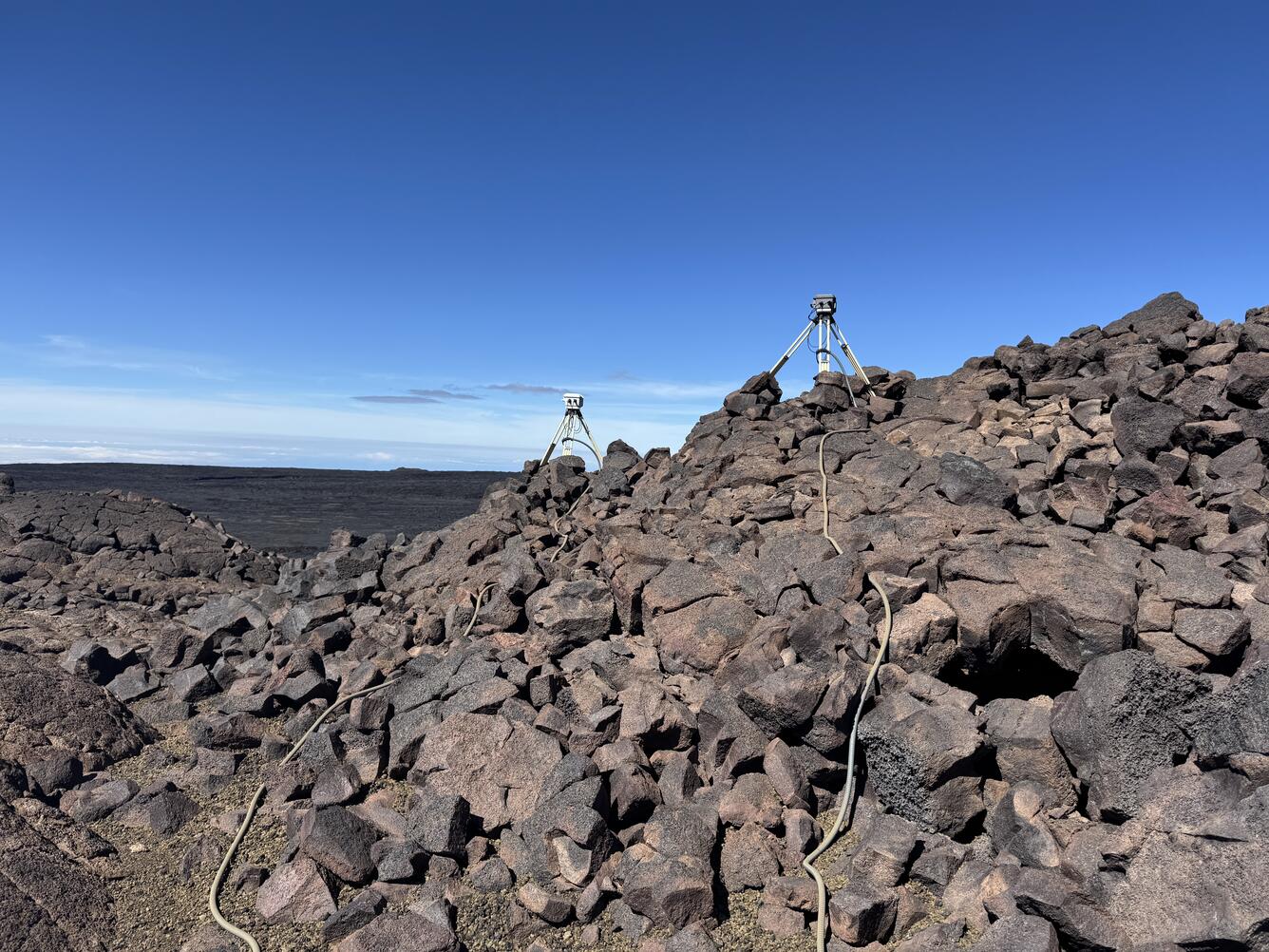Color photograph of volcano monitoring equipment on lava flows