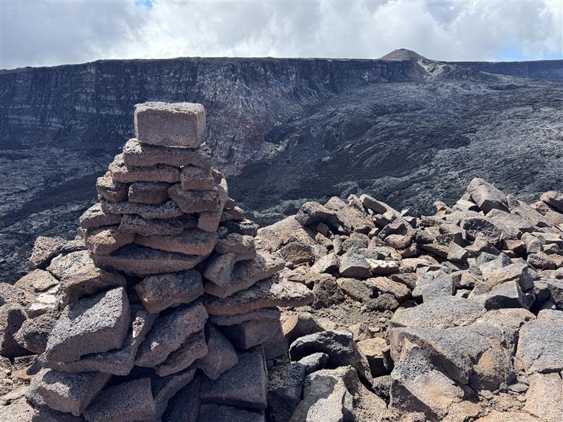 Color photograph of trail cairn near volcanic caldera
