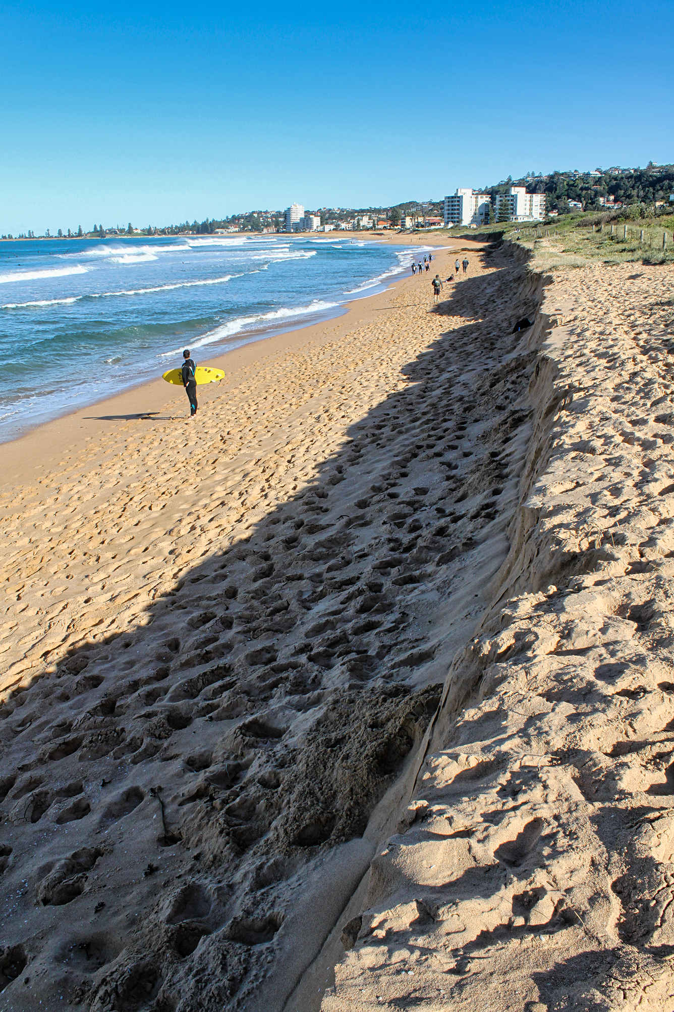 A gently curving beach shows erosion; part of the dune was cut away by recent storms.