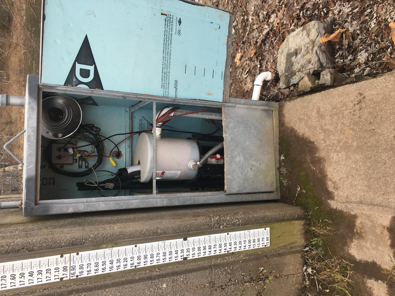 Looking at scientific equipment inside a steel shelter set against the back of the gage house