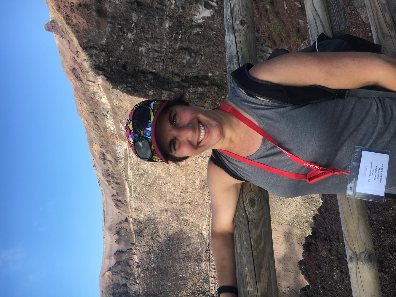 woman standing on edge of volcanic crater with colorful hat. 