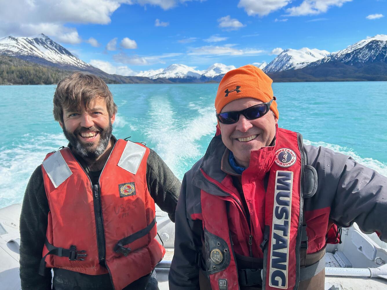 two people in life jackets smile for a photo out on the water