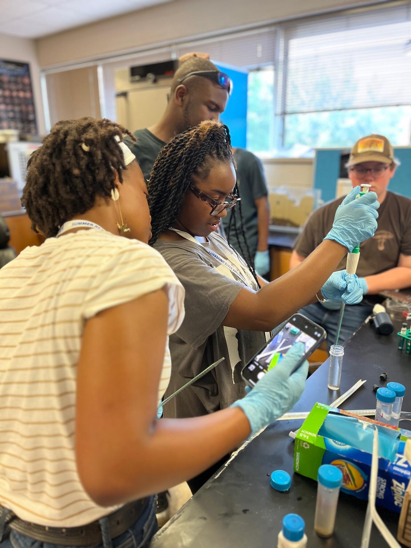 Students in a laboratory wearing gloves do an experiment with scientific devices