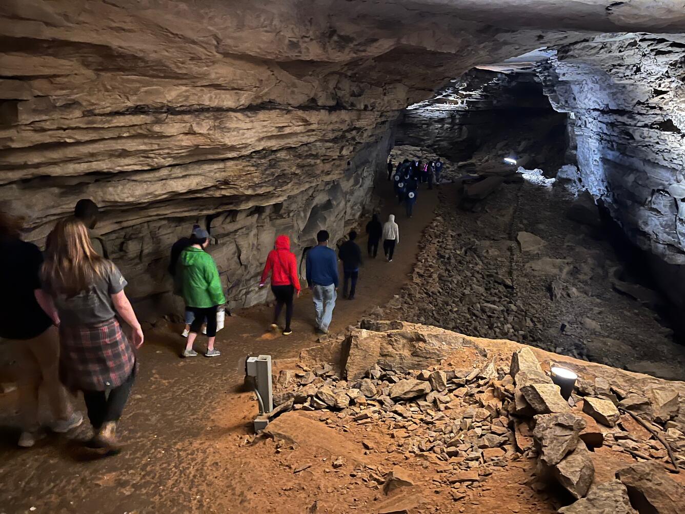 A group of students walk into a dimly-lit cave. 