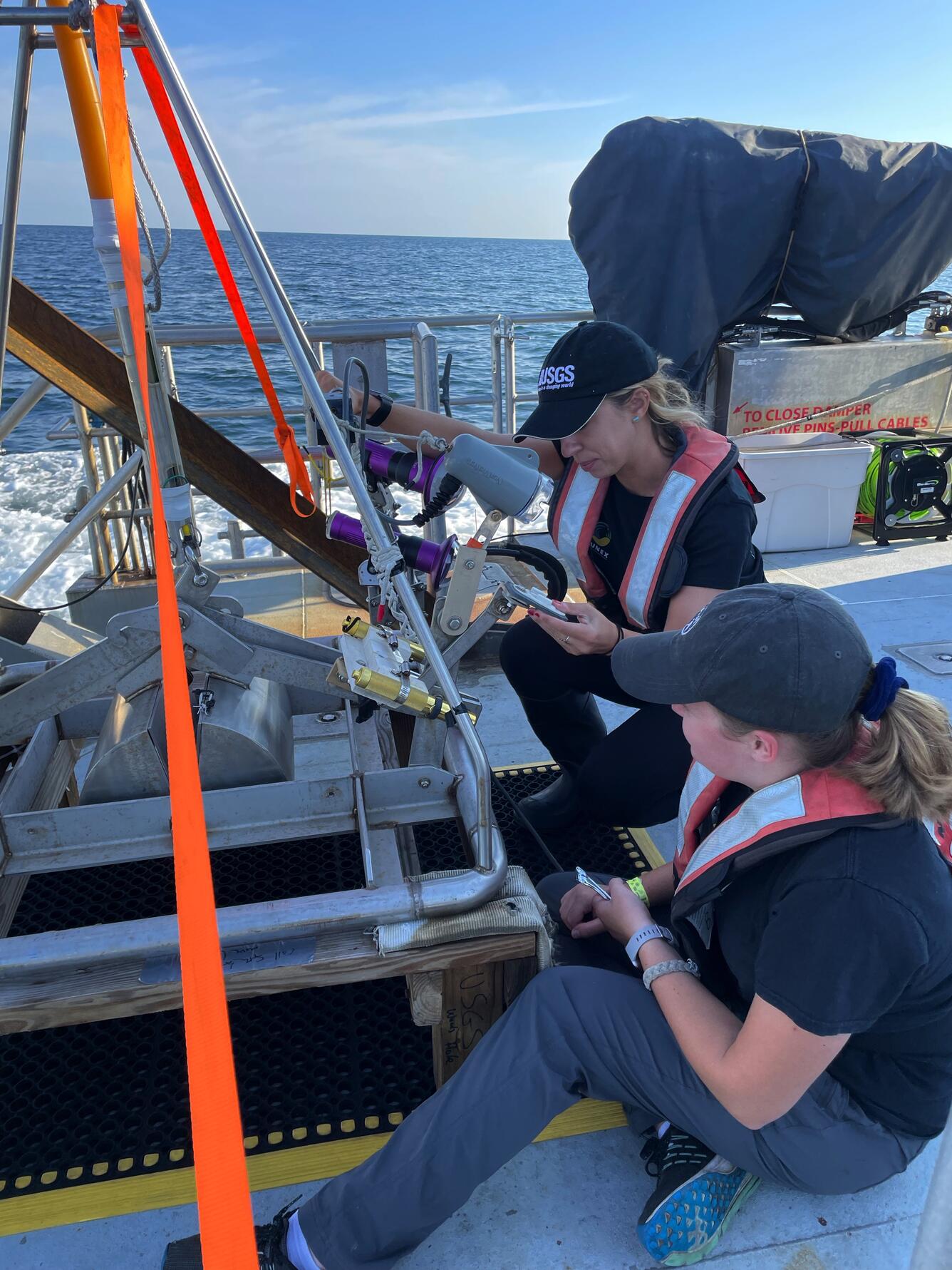 2 women on the deck of a ship setting up data collection equipment